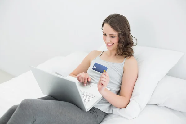 Mujer joven casual haciendo compras en línea en la cama —  Fotos de Stock