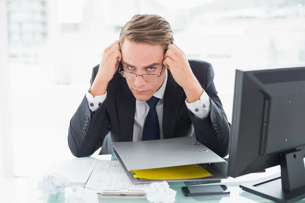 Besorgter Geschäftsmann mit Dokumenten am Schreibtisch — Stockfoto