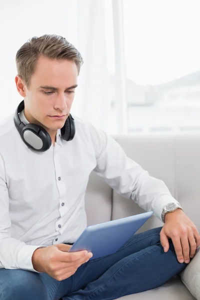 Casual serious young man using digital tablet on sofa — Stock Photo, Image