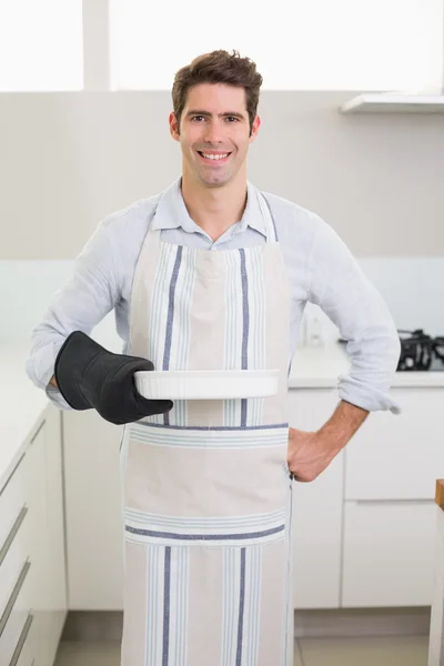 Man smelling food in baking dish in kitchen — Stock fotografie