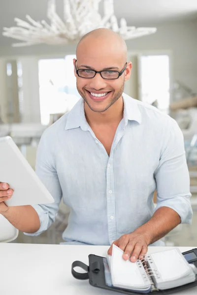 Uomo sorridente casuale con tablet digitale e diario a casa — Foto Stock