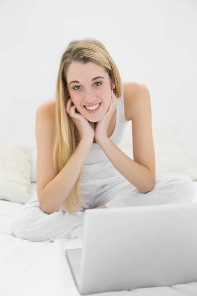 Schöne Frau auf ihrem Bett liegend mit ihrem Laptop — Stockfoto