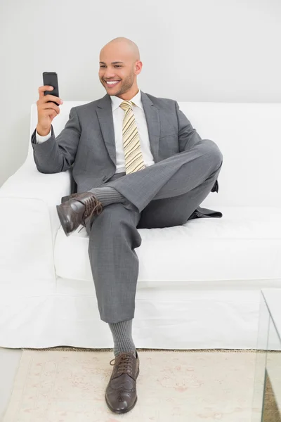 Podnikatel textových zpráv doma na pohovce — Stock fotografie