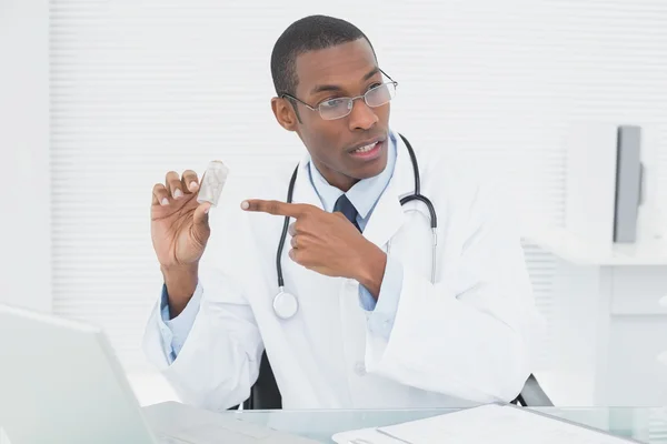 Doctor pointing at prescription bottle in medical office — Stock Photo, Image