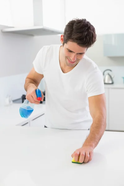 Sorrindo jovem limpeza balcão da cozinha — Fotografia de Stock