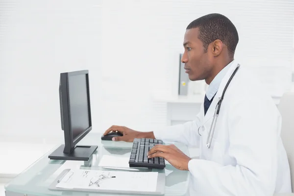 Концентрований лікар за допомогою комп'ютера в медичному кабінеті — стокове фото