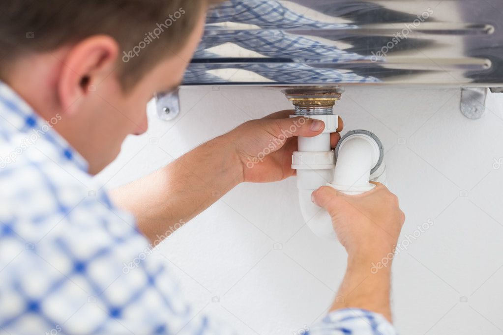 Plumber's hands and washbasin drain at bathroom