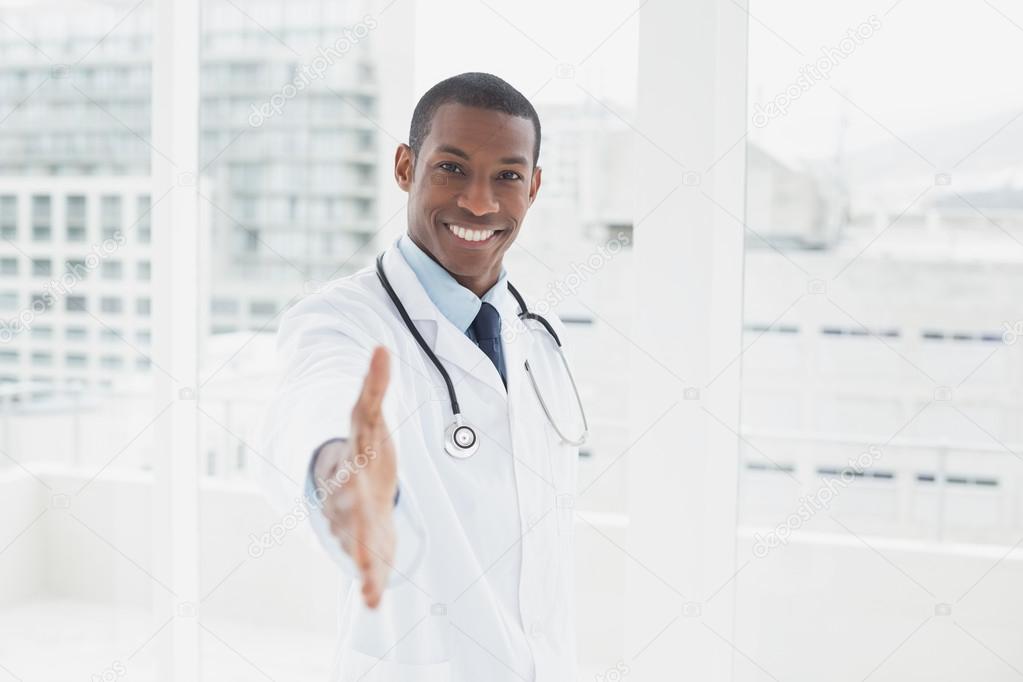 Smiling doctor offering a handshake in a medical office