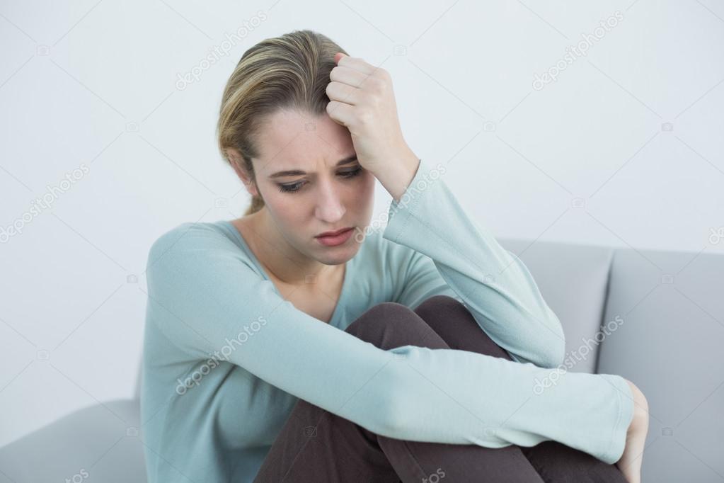 Troubled casual woman sitting on couch