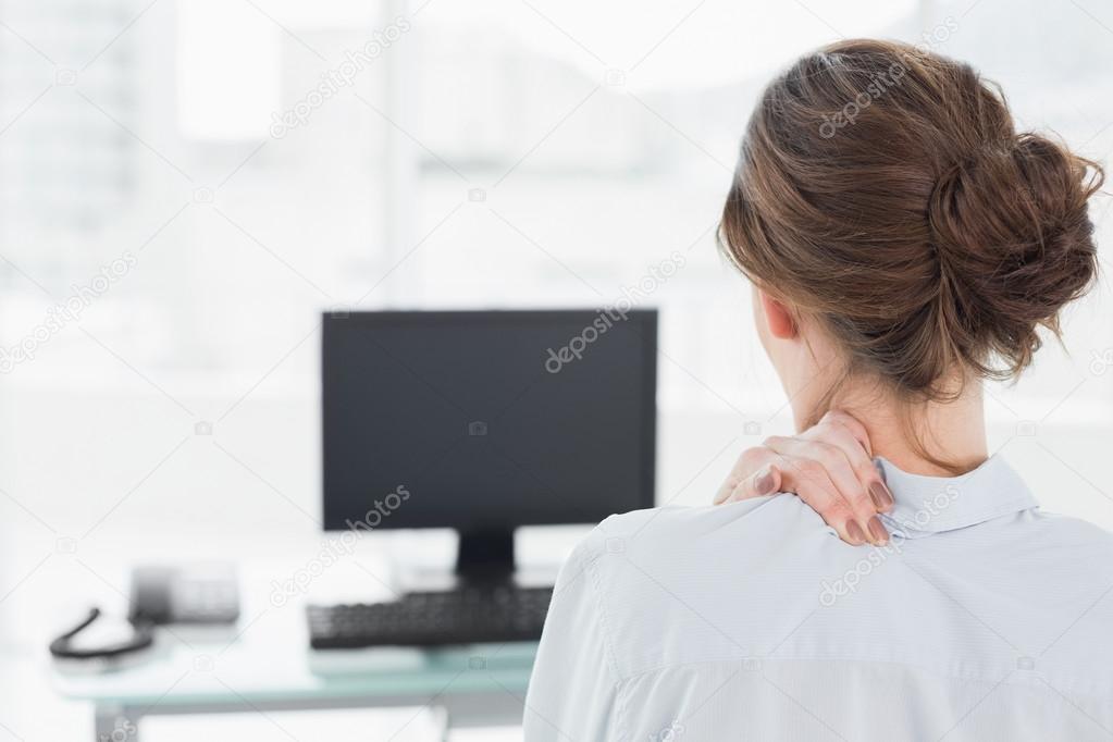 Rear view of a businesswoman with neck pain in office