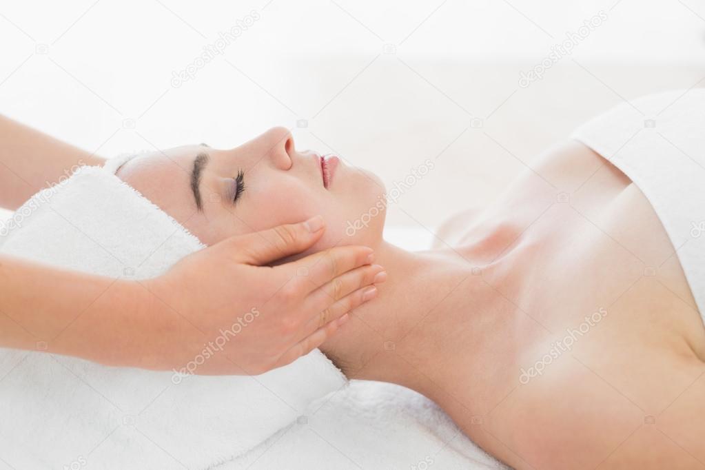 Hands massaging woman's face at beauty spa