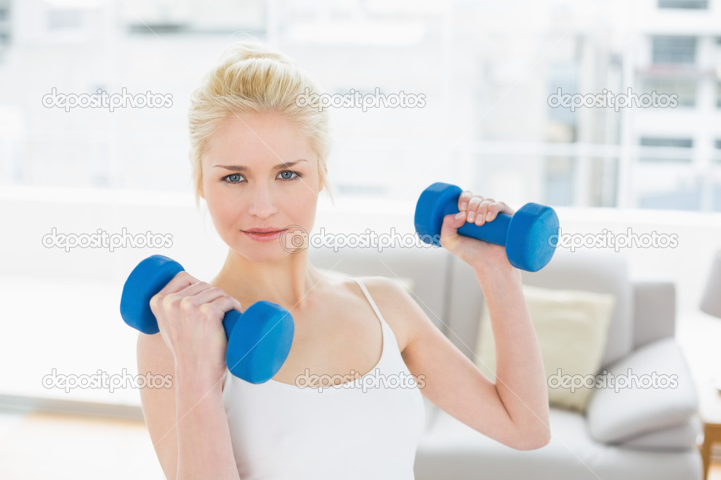 Smiling woman with dumbbells at fitness studio