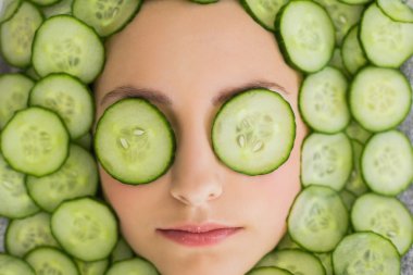 Beautiful woman with facial mask of cucumber slices on face clipart