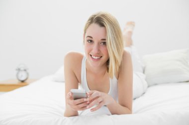 çekici bir kadın kameraya gülümseyen onun smartphone kullanarak