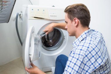 Çamaşır makinesini tamir eden teknisyen.