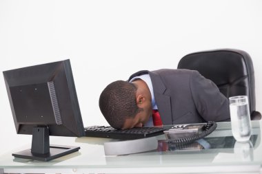 Afro businessman resting head on keyboard in office