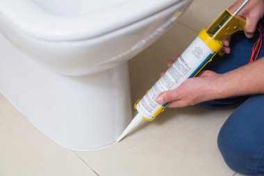 Plumber fixing toilet in a washroom with silicone cartridge clipart