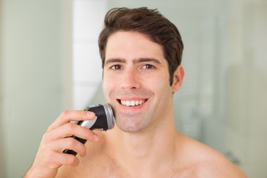 gülümseyen yakışıklı gömleksiz adam elektrikli ustura ile tıraş