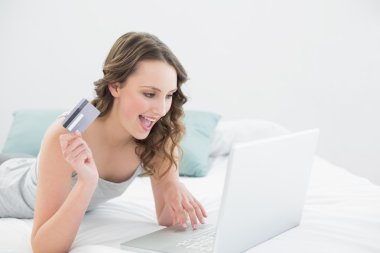 yatakta online alışveriş yaparken rahat genç kadın