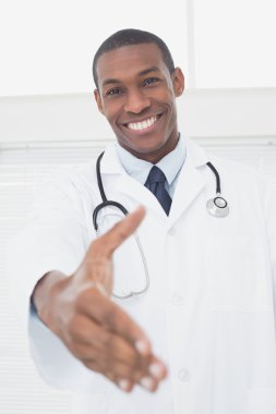 bir el sıkışma sunan gülümseyen erkek doktor