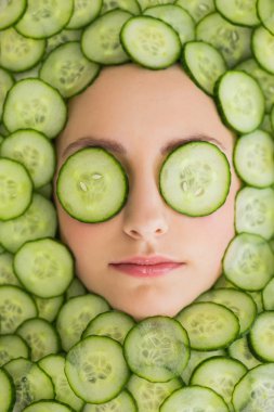 Beautiful woman with facial mask of cucumber slices on face clipart