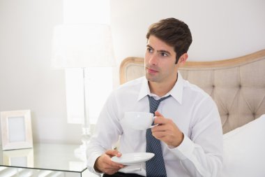 iyi giyimli adam yatakta kahve içme gülümseyen