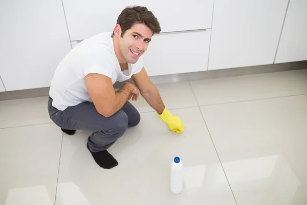 Sonriente joven limpiando el piso de la cocina — Foto de Stock