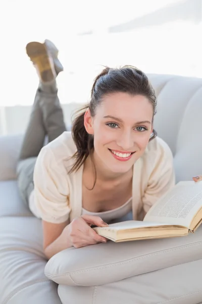 Porträtt av en casual kvinna läser en bok på soffa — Stockfoto