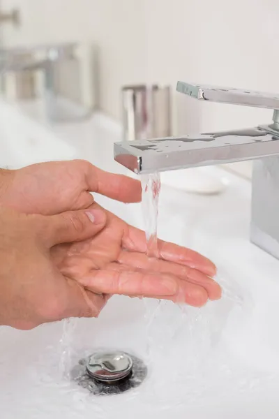 Mano bajo el agua corriente en el lavabo del baño — Foto de Stock