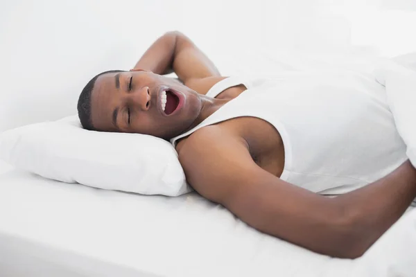 Slaperig afro man geeuwen in bed — Stockfoto