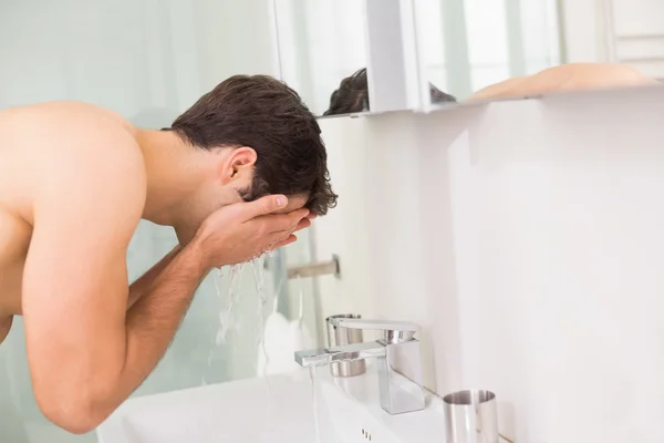 Shirtless young man washing face in bathroom — Stock Photo, Image