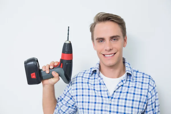 Sonriente joven manitas guapo sosteniendo taladro — Foto de Stock