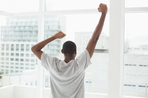 Rear view of Afro man stretching his arms near window — Stock Photo, Image