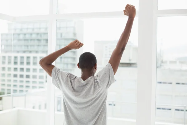 Vista trasera del hombre afro estirando sus brazos cerca de la ventana — Foto de Stock