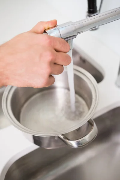 Hand fylla kastrull med vatten på diskbänken — Stockfoto