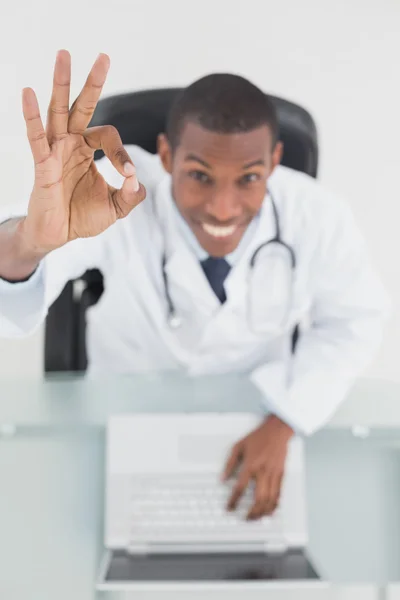 Overhead of a smiling doctor with laptop gesturing okay sign — Stock Photo, Image