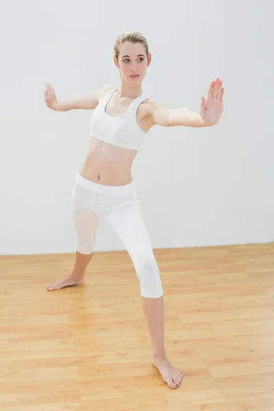 Mujer en forma enfocada practicando yoga de pie en el pabellón deportivo —  Fotos de Stock