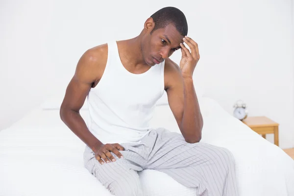 Афромужчина, страдающий головной болью в постели — стоковое фото