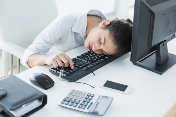 Affärskvinna vilar huvudet på tangentbordet i office — Stockfoto