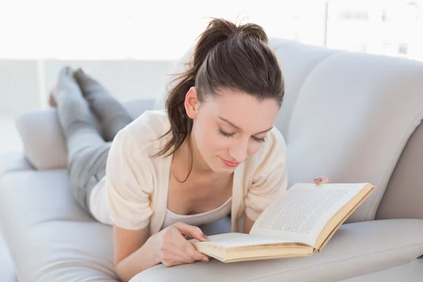Olvasson egy könyvet a díványon, nyugodt alkalmi nő — Stock Fotó