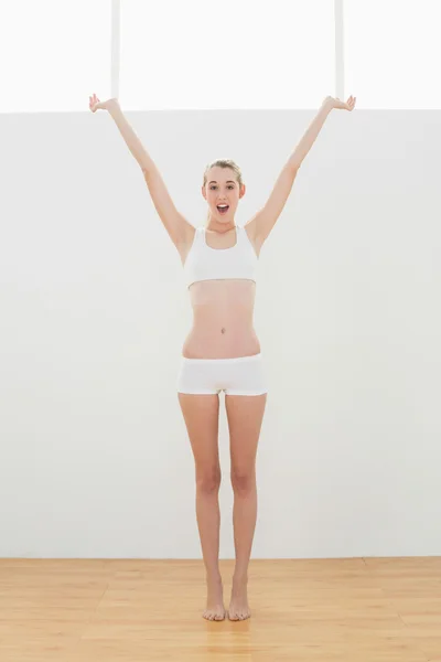 Gleeful fit woman in sportswear stretching raising her arms — Stock Photo, Image