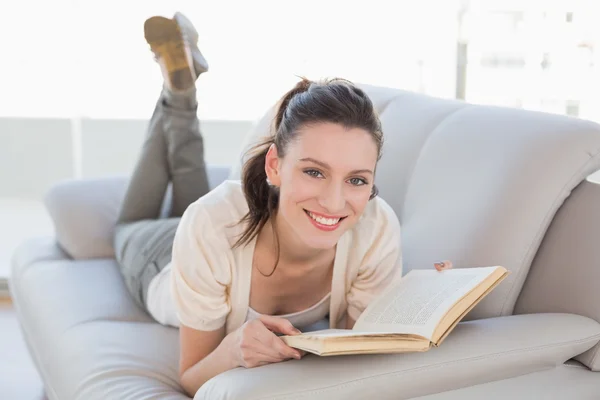 Портрет случайной женщины, читающей книгу на диване — стоковое фото