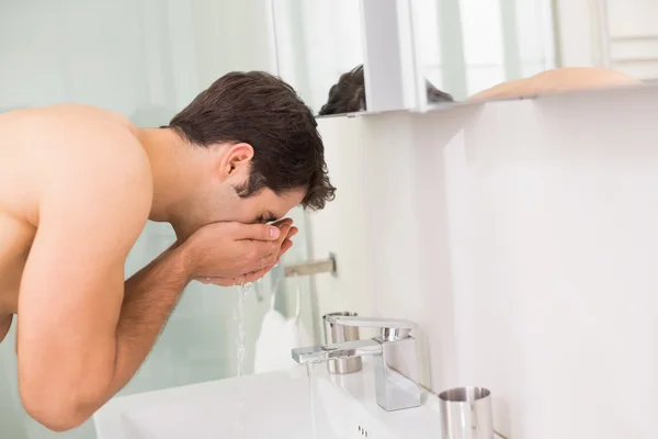 Gömleksiz genç adam tuvalette yüz yıkama — Stok fotoğraf