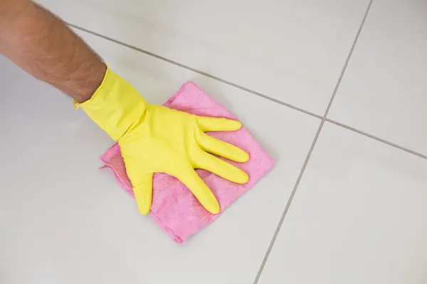 Gele gehandschoende hand met het schoonmaken van rag vegen de vloer — Stockfoto