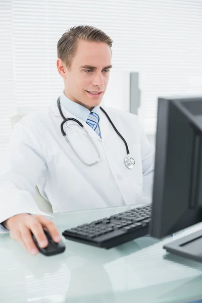 Улыбающийся врач-мужчина с компьютером в медицинском кабинете — стоковое фото