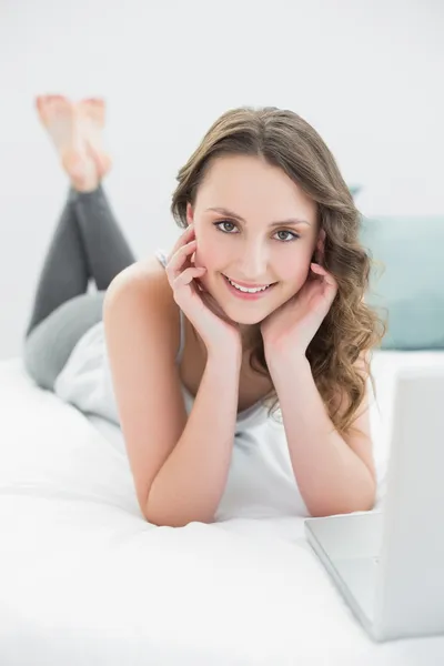 Thoughtful casual brunette with laptop in bed — Stock Photo, Image
