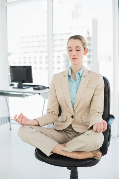 Bella donna d'affari di classe meditando in posizione di loto sulla sua sedia girevole — Foto Stock