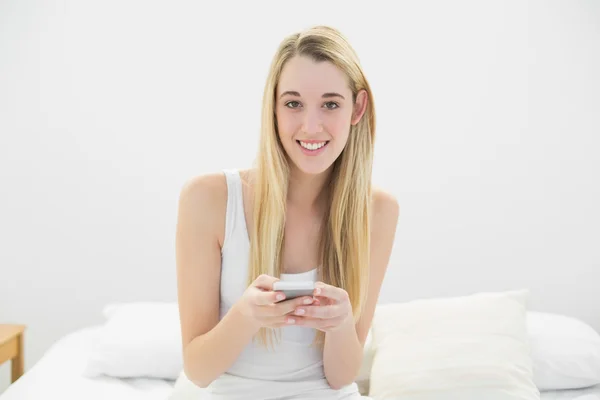 Mooie blonde vrouw op zoek geschokt door haar smartphone — Stockfoto