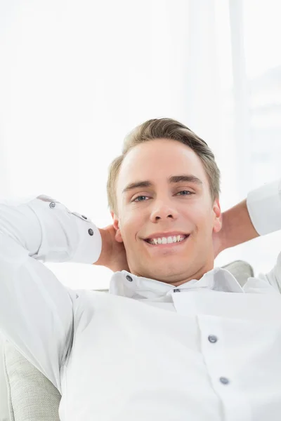Smiling relaxed young man lying on sofa — Stock Photo, Image
