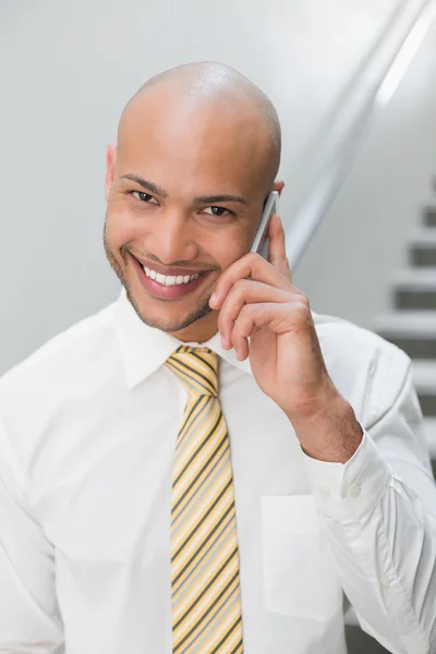 Hombre de negocios sonriente usando el teléfono celular en la oficina —  Fotos de Stock